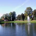 Panorama parku z fontanną na pierwszym planie.